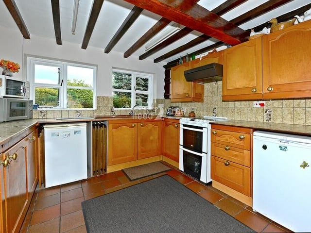 The obligatory ceiling beams look down on the kitchen, which is a busy space. It is fitted with a range of wall and base units in a wood finish, co-ordinating work surfaces, and also a double sink with single drainer and mixer tap.