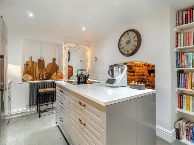 The main kitchen area also features an island with induction hob and base units and drawer beneath, plus an original open fireplace in brick.