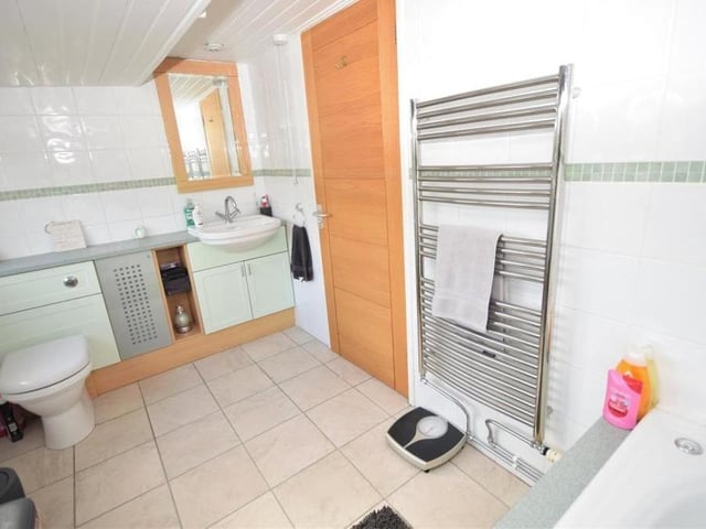The family bathroom from a different angle. Smart and functional, it also boasts a wash basin, set in a useful vanity unit, a low-flush WC and chrome, heated towel-rail.