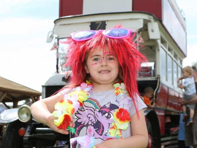 A colourful Mia Thompson in front of a vintage bus from Nottingham Bus Museum at Ravenshead Primary School's summer festival.