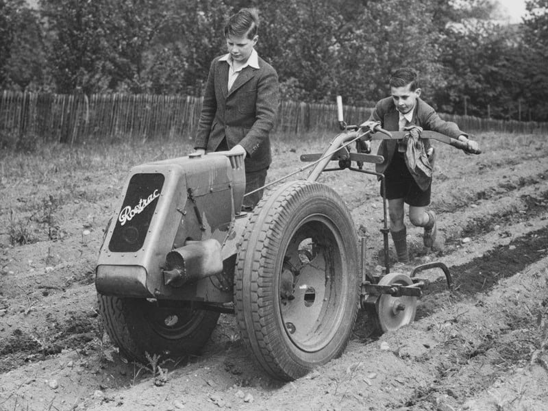 Evacuee schoolboys from London at work using a motorised Rowtrac harrowing machine on the grounds of the Ashley House School for the Dig for Victory campaign on 11th August 1941 in Worksop.