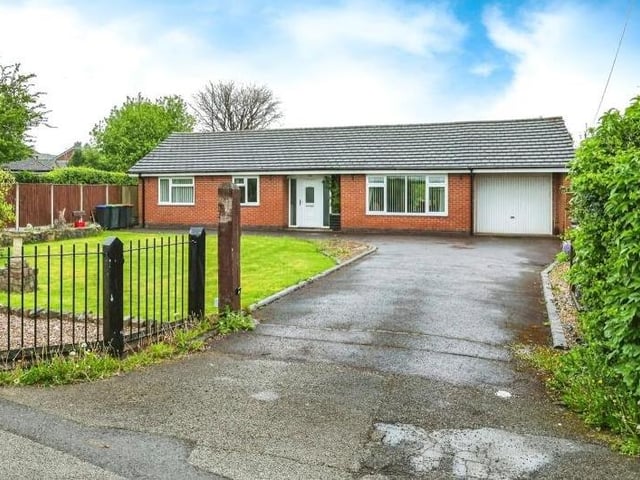 Let's return to the front of the bungalow for the last photo in our gallery. Behind gated access, a lawned garden sits next to a concrete driveway that provides off-street parking space and leads to an integral garage with up-and-over door, power and lighting. At the back of the garage are double doors leading out to the rear garden.