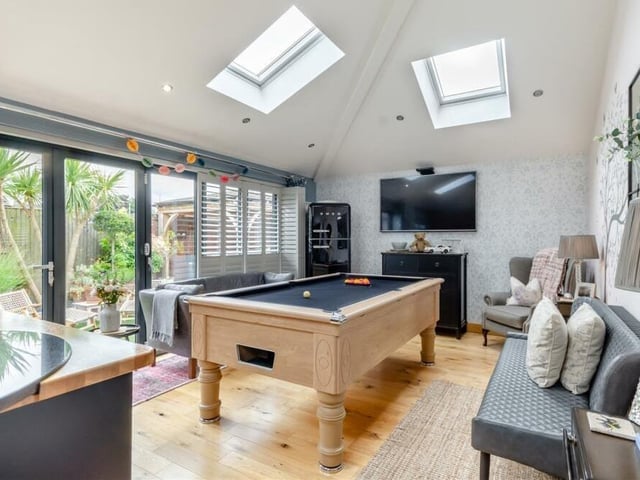 Here is the attractive living space that is part of the open-plan extension. Large bi-folding doors lead out to the landscaped rear garden, while the windows are fitted with high-quality shutters. As you can see, there is space for a pool table or snooker table.