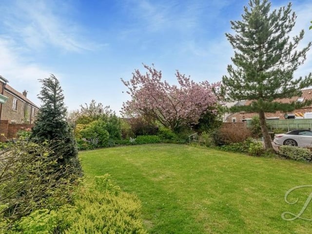 The front garden is a splendid mix of lawn, trees and bushes and shrubs.