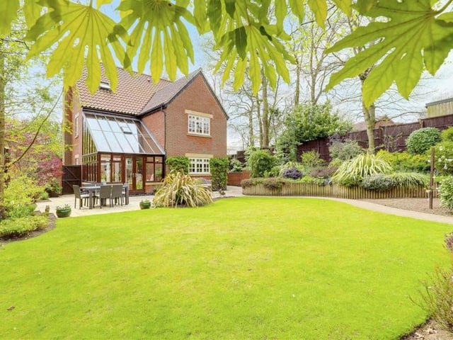 Stepping outside now and what a beautiful sight the private, landscaped back garden makes. It features multiple patio areas, a lawn and a range of decorative plants and shrubs, mature trees and raised planters