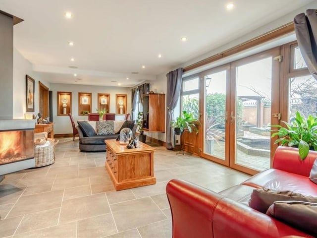 The first reception room we look at this substantial open-plan living room and dining room. Its features include a modern, wall-hung log-burner, with floor-to-ceiling tiling behind, and double doors that lead out to the garden.