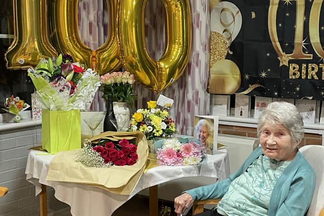Dorothy Adlington, surrounded by flowers and gifts on her 100th birthday last Saturday.