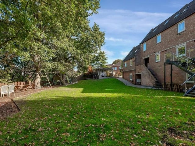 The substantial garden includes a lawn and a children's play area.