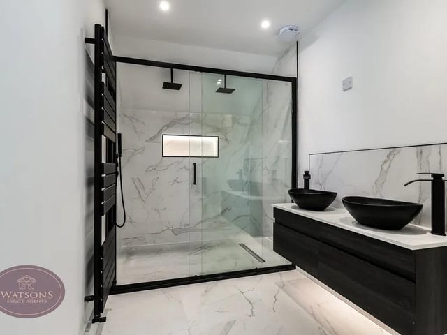 This ensuite features a 3 piece suite comprising; concealed cistern wc, double countertop vanity sink unit with round basins and double walk in shower cubicle with mains fed rainfall shower. Tiled floor, chrome heated towel rail, ceiling spotlights, and extractor fan.