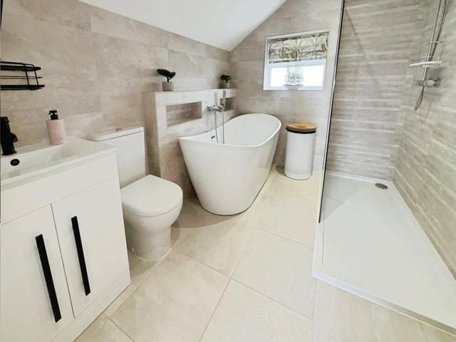 The family bathroom is finished in a refined, modern style, featuring a freestanding slipper bath, a walk-in shower, vanity unit and a WC.