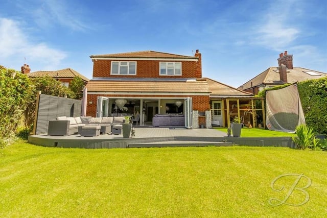 This view from the back garden shows the £595,000 property from the rear, with the large bi-folding doors from the open-plan hub opening out on to a decked seating area in the garden.