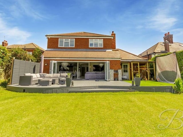 This view from the back garden shows the £595,000 property from the rear, with the large bi-folding doors from the open-plan hub opening out on to a decked seating area in the garden.