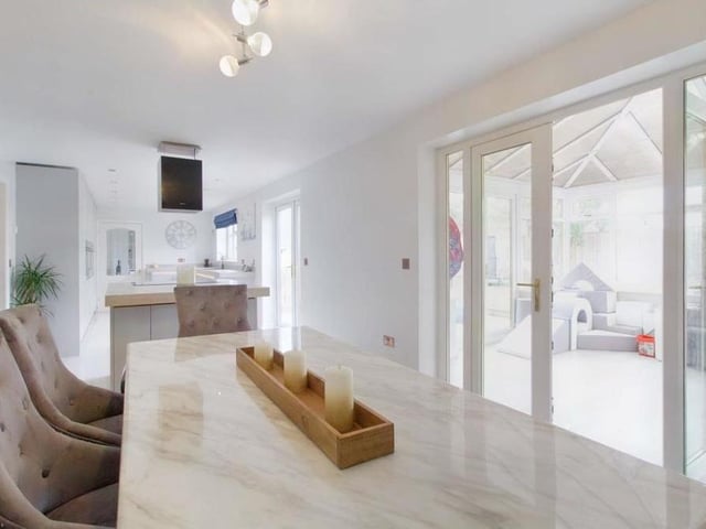 Two sets of French doors in the open-plan kitchen/dining room open into the conservatory and on to the garden