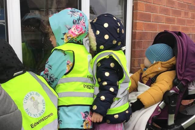 Children from Cherubs Edwinstowe wave at elderly residents through the windows