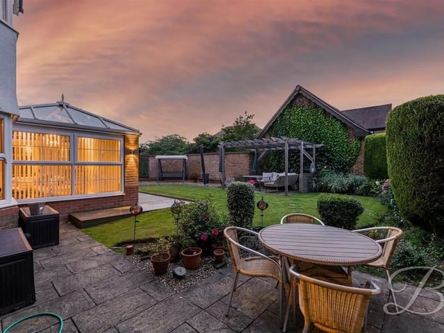 Outside, the garden has been stunningly landscaped with a manicured lawn and a patio area including a pergola above