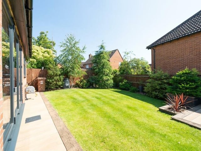 The pleasant rear garden, which features a lawn, trees and shrubs, has been landscaped and extended.
