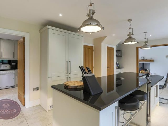 A sleek central island at the heart of the kitchen offers further storage, a breakfast bar and integrated wine-cooler.