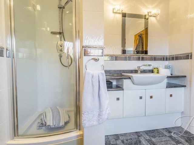 A second picture of the ground-floor en suite bathroom, which shows its enclosed shower cubicle and vanity unit with wash hand basin.