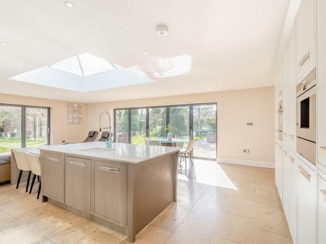 Integrated appliances in the kitchen include a combination microwave oven, two warming drawers, a coffee machine, two ovens, a five-ring gas hob, a custom-made extractor hood with inset spotlights, a fridge and dishwasher. A comprehensive range of contemporary cabinets include wall cupboards, base units and drawers, complemented by quartz worktops.