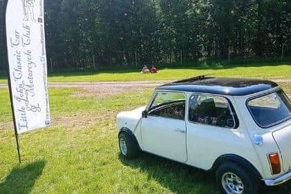 A vintage Mini by the banner of the Little John Classic Car and Motorcycle Club.