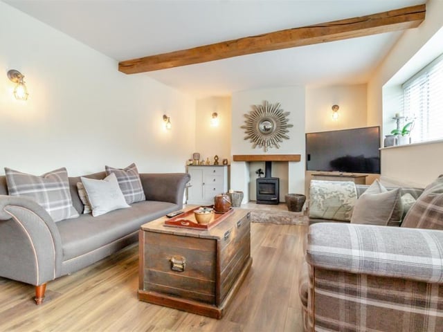 A last look at the relaxing lounge. Two windows face the front of the property, while a cupboard houses a gas meter and there are six wall-lights.