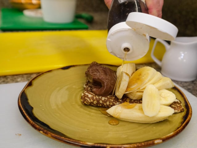 Fold over the pancake and add your toppings of choice. Here, Carl has opted for chocolate spread, banana, and maple syrup.