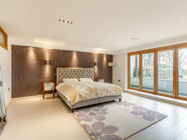 The lower ground floor contains two of the main double bedrooms, including this marvellous master that combines space with style. Assets include a feature wall, Porcelanosa plank tile floor and large, glazed doors leading out to the decked patio in the back garden.