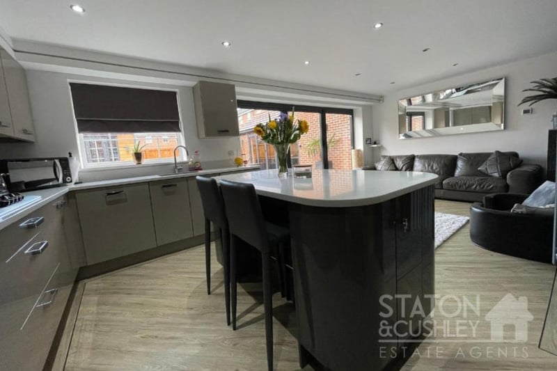 The sleek kitchen is fitted with smart wall and base units, as well as drawers and quartz worktops. At the heart of the room is a breakfast bar island.