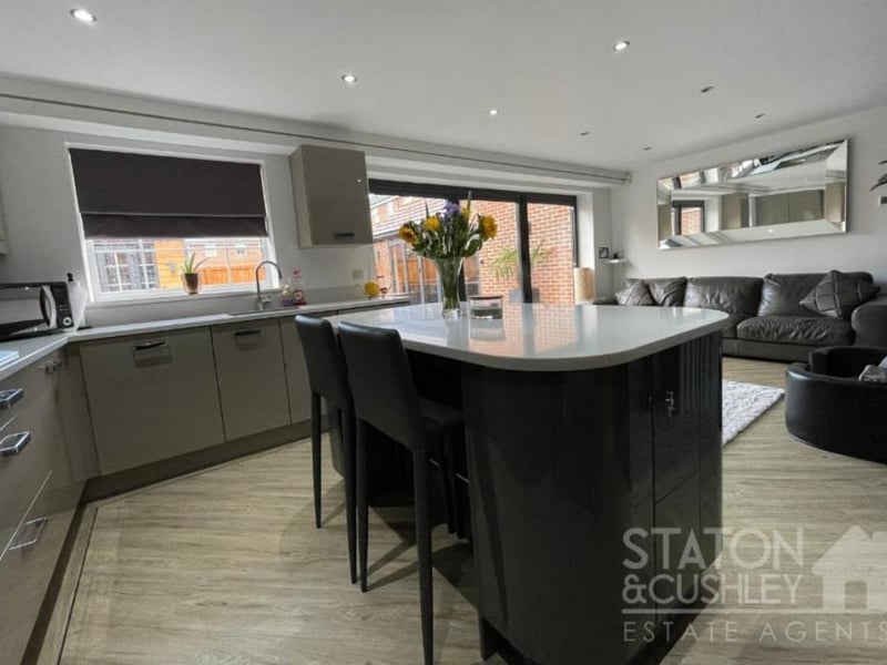 The sleek kitchen is fitted with smart wall and base units, as well as drawers and quartz worktops. At the heart of the room is a breakfast bar island.
