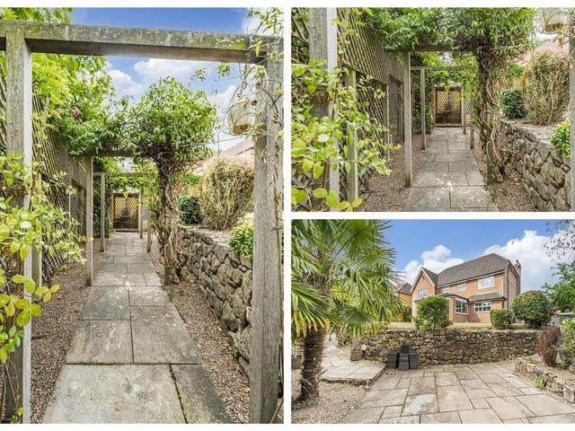 The rear garden is generously sized and beautifully landscaped, offering multiple patio seating areas, a laid lawn, and is enclosed by fencing with mature trees and shrubbery for privacy.
