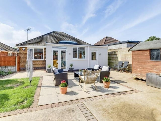This photo shows how French doors from the open-plan kitchen and dining area lead out to the rear garden, which features a small lawn and patio.