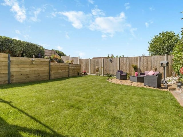 The back garden also features well-maintained lawns with a boundary of timber sleepers.