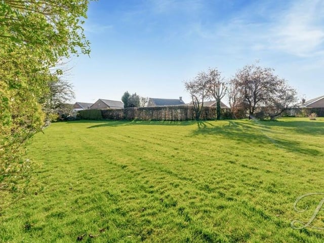 Another look at the extensive lawn, which is surrounded by a beautiful display of mature shrubs and trees.