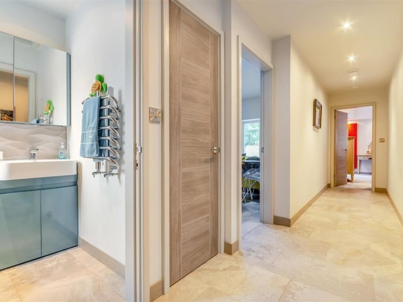 Through the front door, this inviting entrance hall guides you to all of the main rooms in the £645,000 bungalow. There's an in-built cloaks cupboard with shelves, a consumer unit housing the central heating boiler, a Porcelanosa tiled floor and five ceiling spotlights.