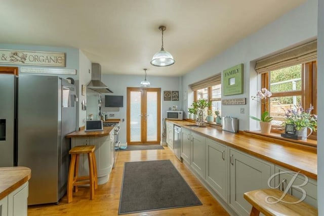 The kitchen blends space and style. Appliances include a gas hob and extractor fan,while double windows overlook the back of the house and a door leads outside. There is plumbing for a dishwasher too.