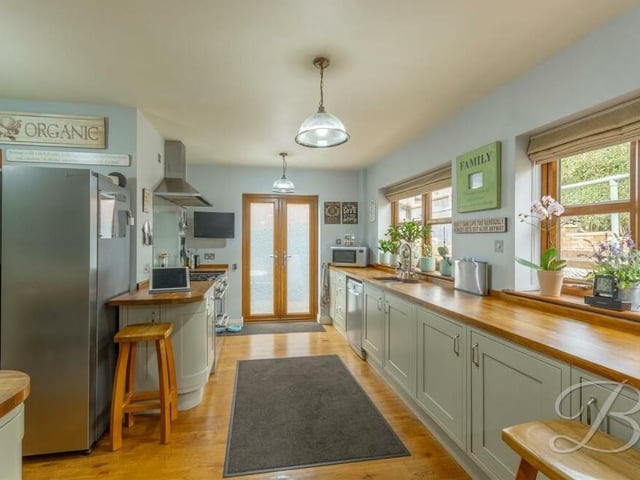 The kitchen blends space and style. Appliances include a gas hob and extractor fan,while double windows overlook the back of the house and a door leads outside. There is plumbing for a dishwasher too.