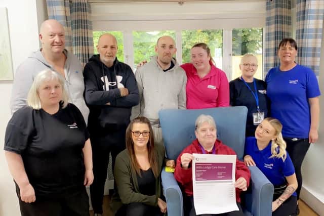 Manager Leanne Dodsworth (kneeling, left), staff and residents at Willis Lodge care home in Kirkby proudly show off a print-out of the Care Quality Commission report.
