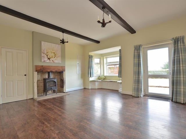 We begin our tour of The Old Farmhouse in this delightful dining room, with its feature fireplace, beamed ceiling, laminate floor and door leading out to the garden.