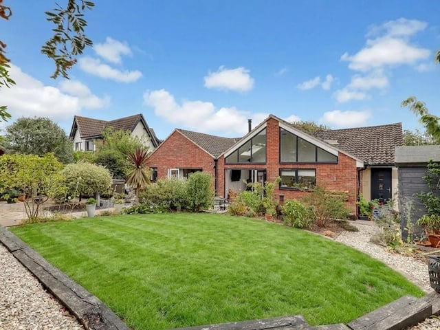 Steps lead up from the patio to a well-maintained lawned area, complemented by planted borders and gravelled sections.