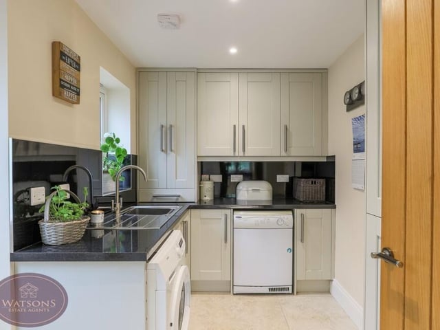Just off the kitchen is this useful utility room, with space for a washing machine and tumble dryer. It also contains a concealed, wall-mounted combination boiler, matching wall and base units, work surfaces, and a stainless steel sink and drainer unit