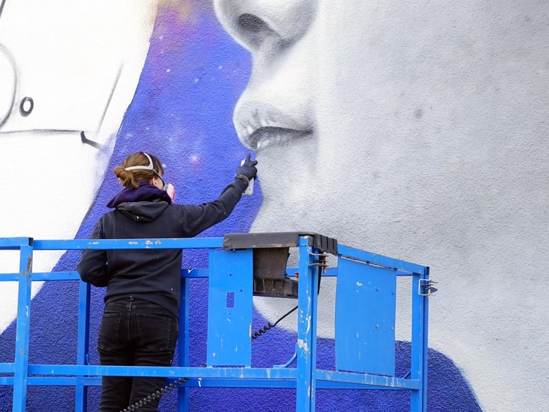 Zabou - a French artist is seen painting a mural on a building at Sutton.