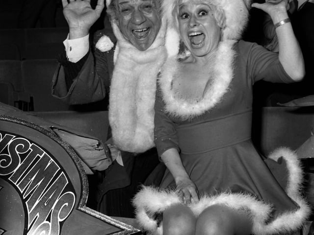 Carry On stars Sid James and Barbara Windsor welcoming guests to a party for ITV's Christmas performers at the New London Theatre in 1973.