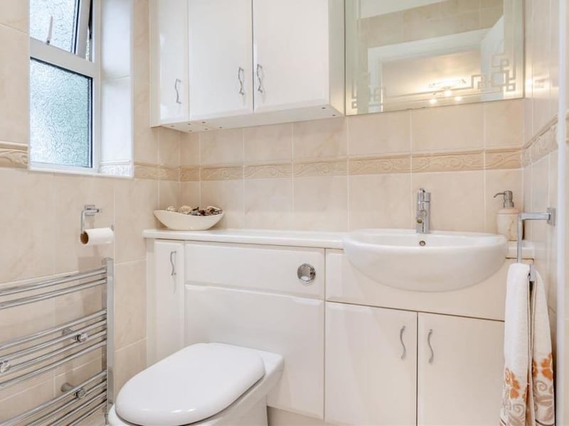 Here is the classy en suite to the master bedroom. A contemporary three-piece suite comprises a tiled shower cubicle, vanity unit with wash hand basin, work surface and storage cupboard beneath, and also a low-flush WC. Additional storage units, a chrome, heated towel-rail, fully tiled walls and ceiling spotlights add to its appeal.