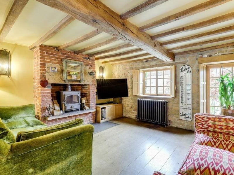 Across from the sitting room is this lovely living room, where the focal point is a recessed chimney-breast alcove, featuring a log-burner stove and an exposed brick surround. It also boasts a solid oak floor, a cast-iron column radiator and exposed oak beams to the ceiling.