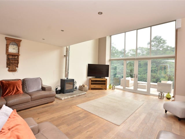 The living room is flooded with natural light thanks to the floor to ceiling windows, and features doors leading out to the outdoor terrace, as well as a log burner for cosy evenings.