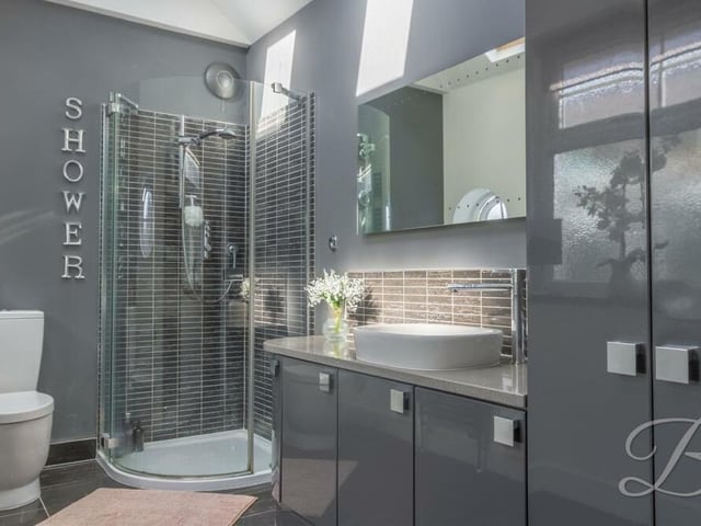 The shower room is sparkling and contemporary. It features an enclosed shower, a hand wash basin and a low-flush WC, plus a cupboard for additional storage,.