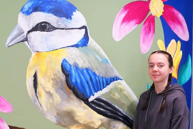 Kiera alongside the boldly coloured mural in the cafe at Vicar Water
