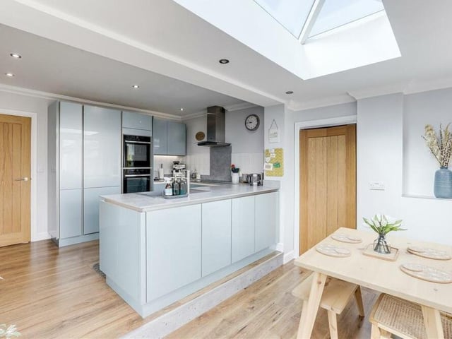 This photo shows how the kitchen flows, open-plan-style, into the dining area, where there is space for a table and chairs. Features include underfloor heating, with a wall-mounted digital thermostat, and recessed spotlights.
