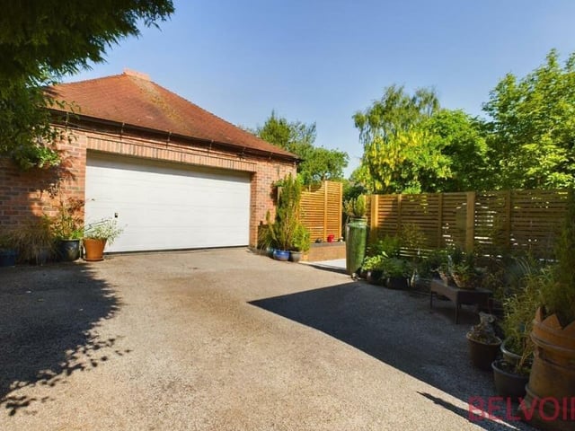 The driveway leads to a double garage, with remote-controlled roller-door. It has a full-width workbench at the back, plus extra storage space in the rafters.