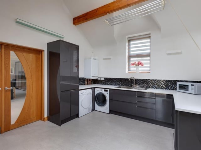 Not many utility rooms look as stylish as this one, particularly with its high ceiling, exposed timber beams and Velux roof window. Sitting just off the breakfast kitchen, it is fitted with a range of wall and drawer units, and matching work surfaces. There's also space for an automatic washing machine and tumble dryer, while above the units is a Baxi boiler.